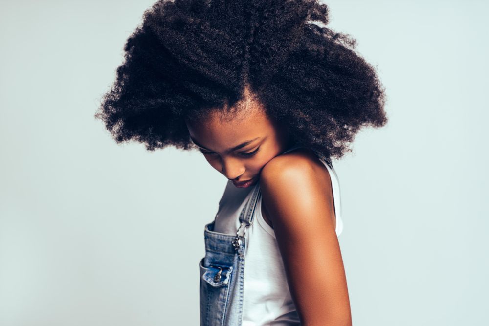Studio portrait of girl looking down in jean overalls