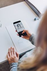 Woman with smartphone taking photo of paper with sketch