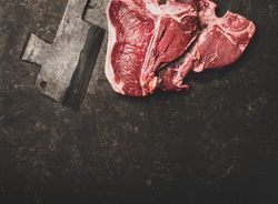 Two T-bone steaks with cleaver on butchers block, square crop with copy space