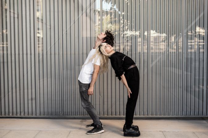 Loving man and woman supporting each other while standing back to back
