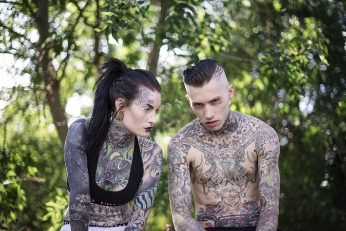 Young edgy white couple covered in full body tattoos posing with tough scowl