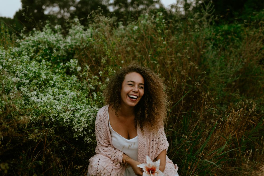 Smiling woman touching flower in forest