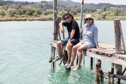 older couple sitting on dock dangling with legs