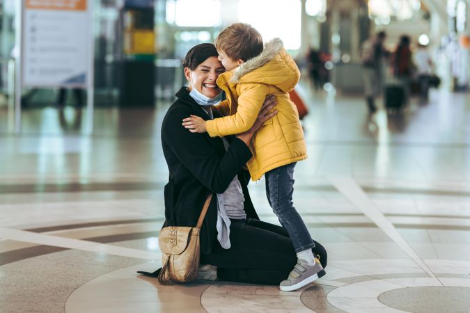 Kid loving his mother sitting on floor at airport