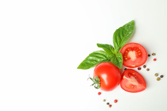 Fresh cherry tomatoes with basil and spices on blank background, space for text and top view. Ripe vegetables