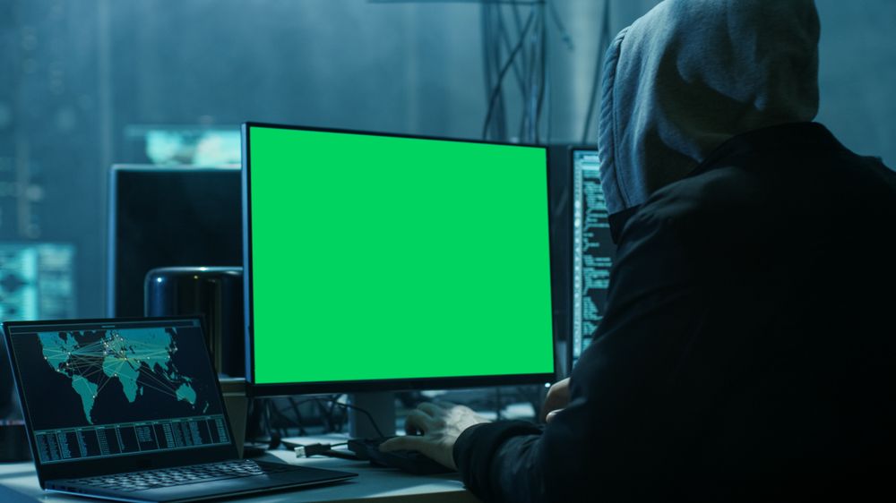 Close-up Shot of Hacker Working with Green Screen Mock-up Display Infect Servers and Infrastructure with Malware.