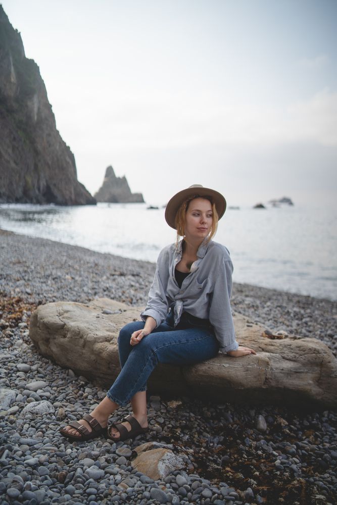 Woman resting on beach stone by sea