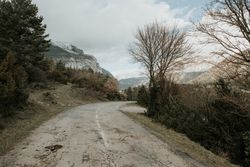 Countryside road on wonderful valley with trees and high hills in cloudy weather