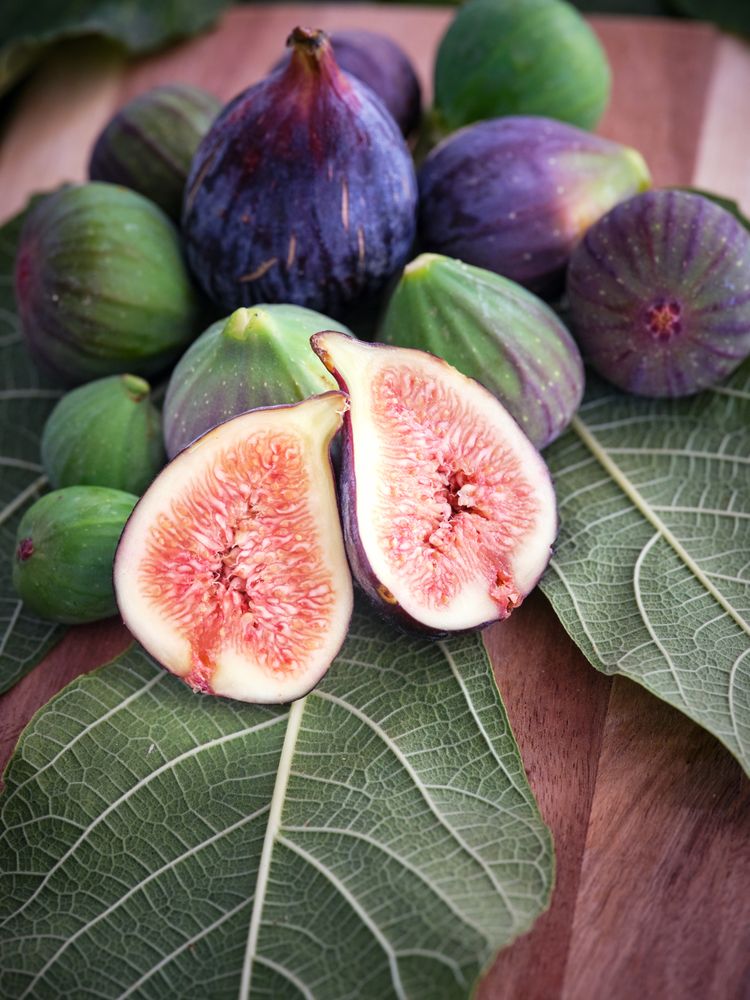Whole and halved figs on wooden surface