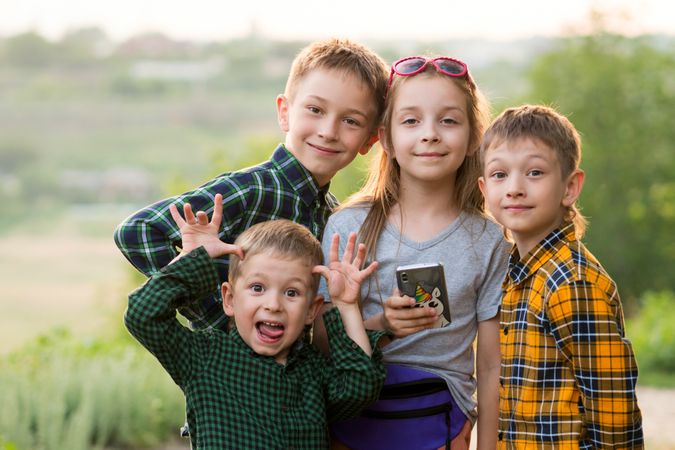 Three brothers and sister sunset together in field