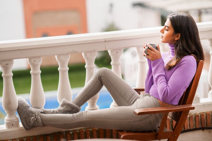 Woman relaxing on outdoor deck with warm beverage