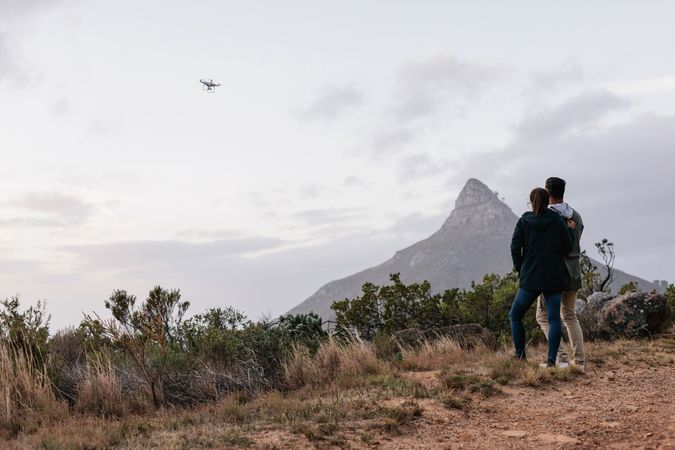A couple using a drone on a hiking trail