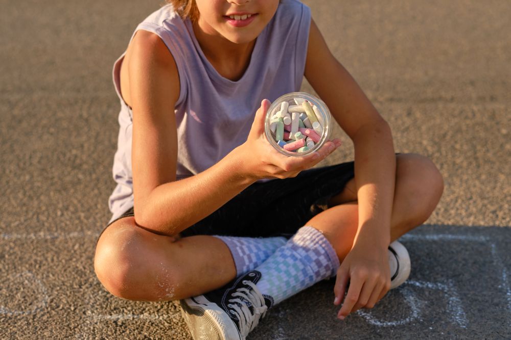 Crop child with chalks in jar