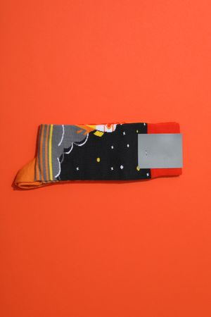 Bright socks with a print, in a pile on an orange background.