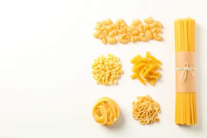 Flat lay composition with different pasta on bright background, space for text