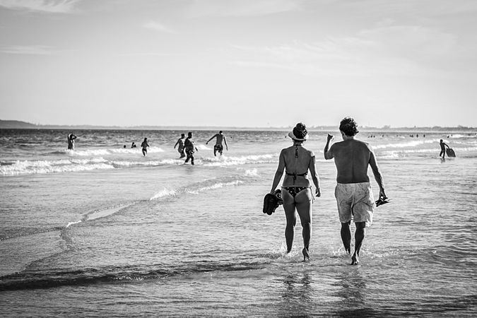 Grayscale photo of man and woman walking on beach