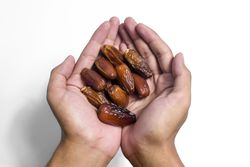 Hand hold date fruit on isolated  plain background