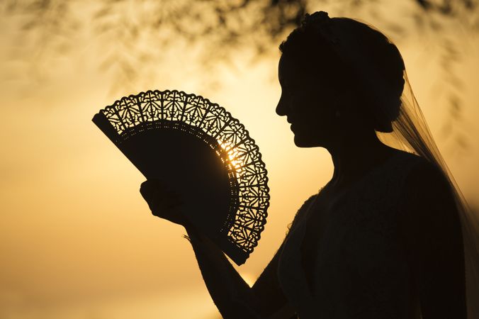 Woman with vintage fan at sunset