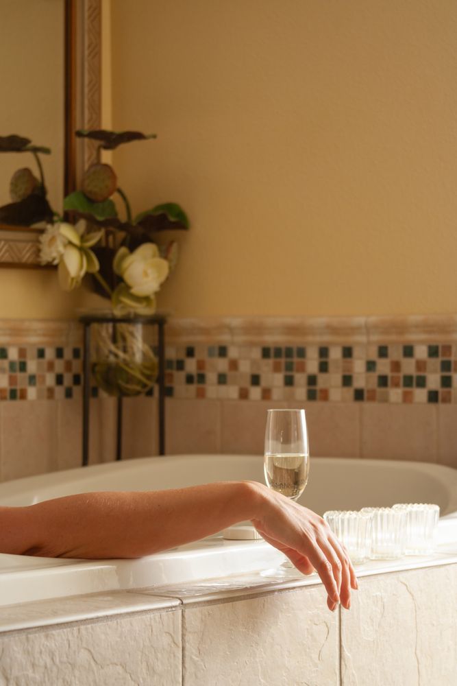 Woman Relaxing in the Bathroom Spa Tub with a Glass of Sparkling Champagne and Candles.