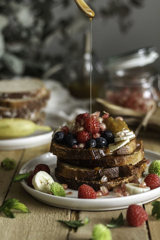 Honey pouring over fried toasts with fruit