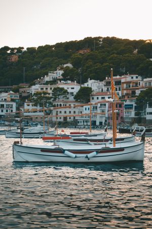 Sailboat on sea water against houses  on rocky shore