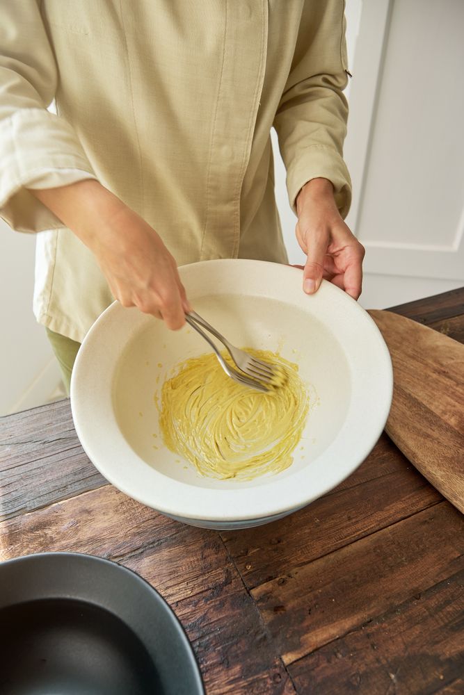 Crop woman mixing mustard sauce in bowl