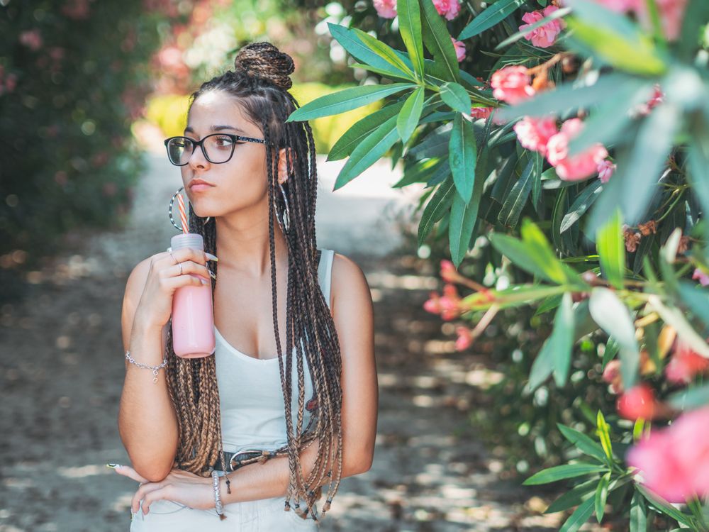 Stylish young woman with dreadlocks and beverage