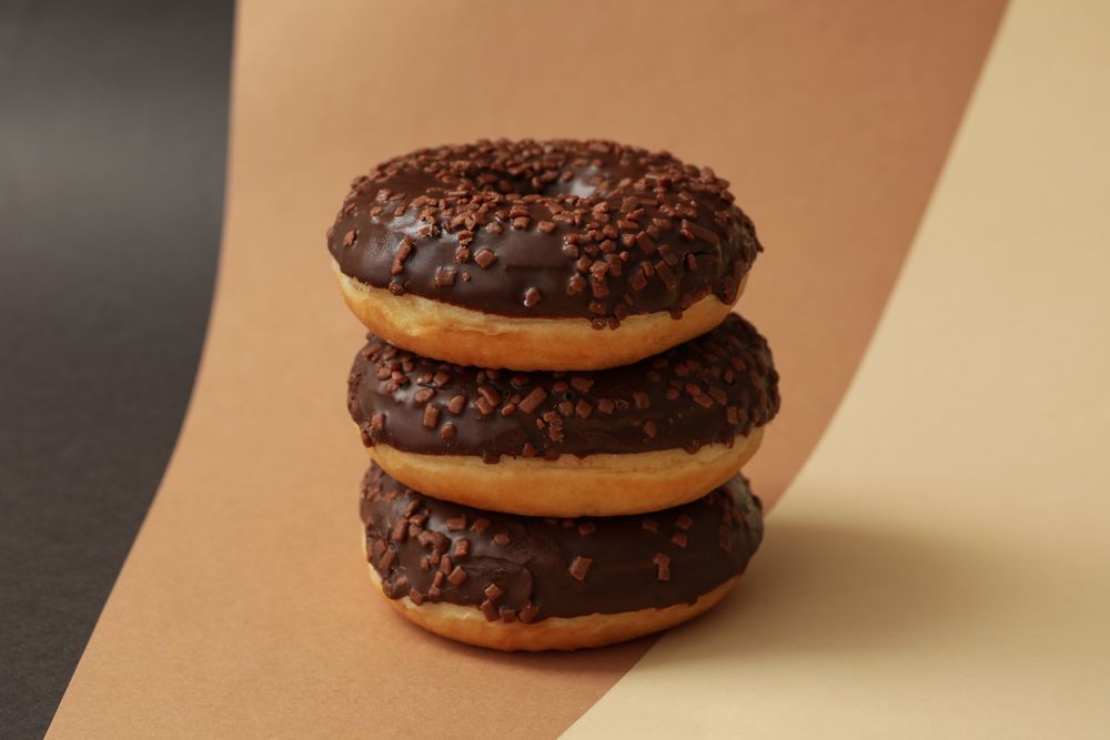 Tasty chocolate donuts on three tone background