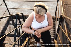 Curvy blond woman checking smart watch on outdoor staircase 47LKAb