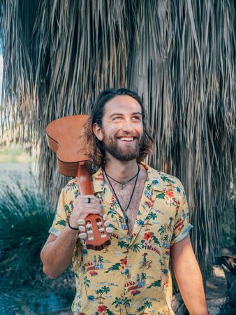 Hipster man in jungle with ukulele