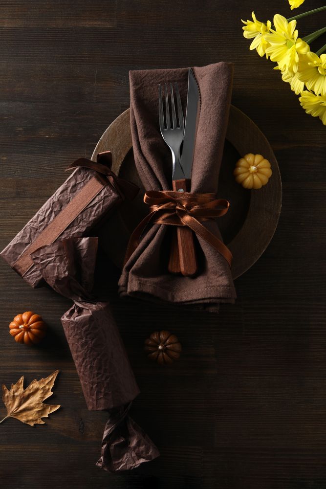 Cutlery on plate, pumpkins and flowers on wooden background, top view