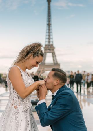 Bridegroom kneeling and kissing hands of bride