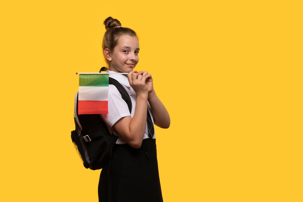 Schoolgirl carries Italian flag on backpack while posing confidently.
