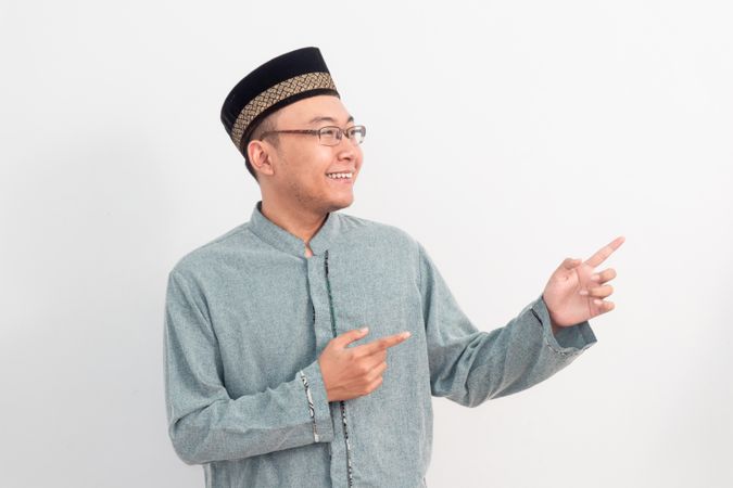 Asian Muslim man smiling doing pointing gesture in Ramadan