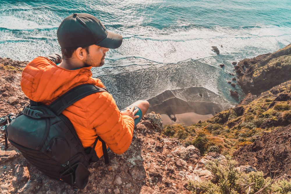 Man carrying backpack on top of mountain