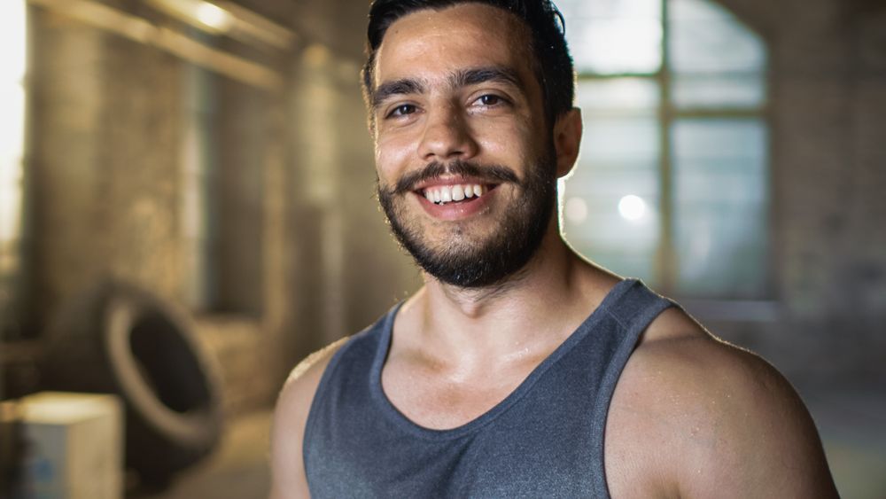 Sweaty Muscular Man Smiles on Camera.