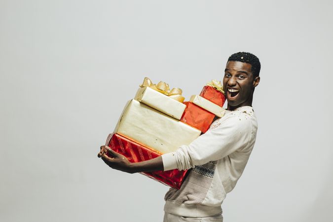 Excited Black man holding a stack of wrapped presents