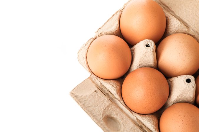 Brown chicken eggs in carton box isolated on light background, top view