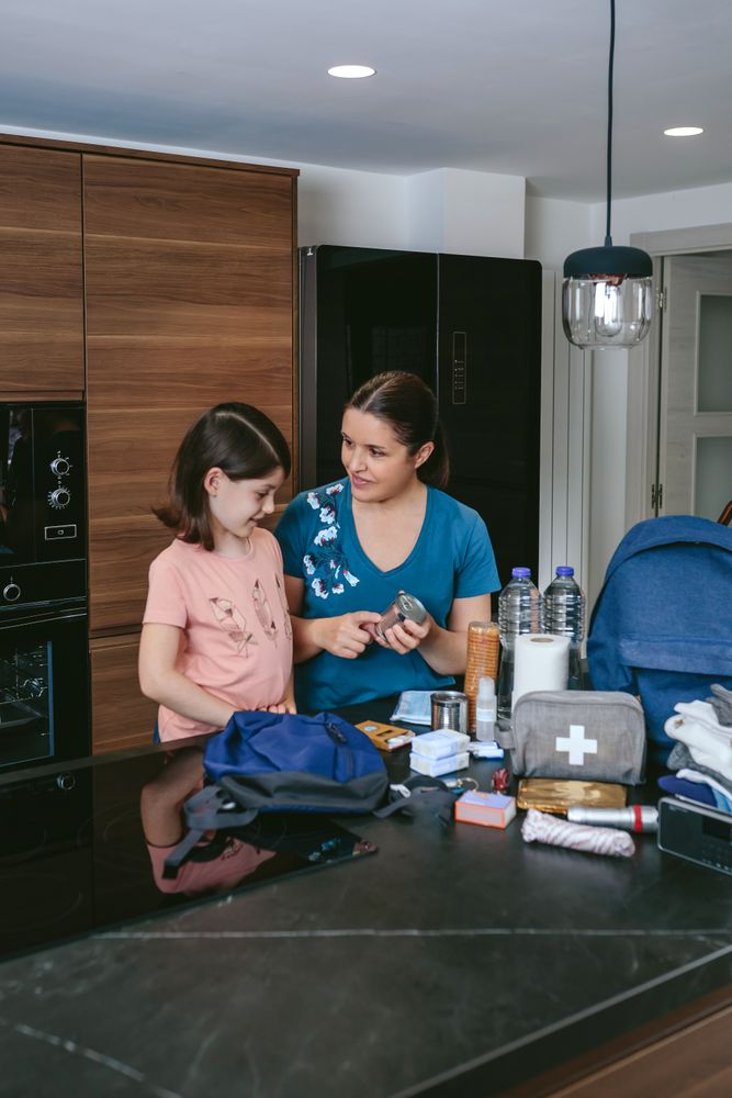 Mother explaining to her daughter how to prepare emergency backpack