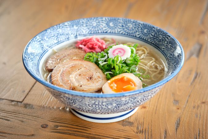 Delicious ramen soup with soft egg and pork meat in bowl
