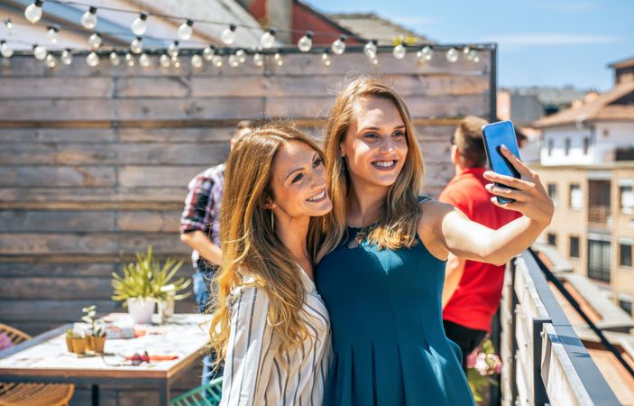 Two female friends taking a selfie in office rooftop on a summer day