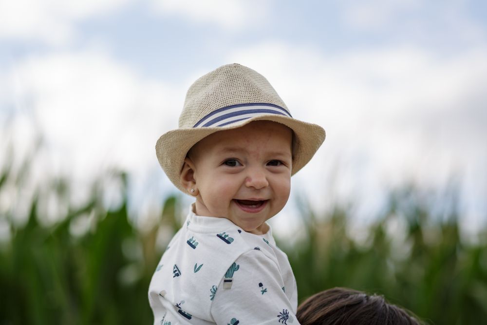 Stylish kid in hat smiling and looking at camera in field