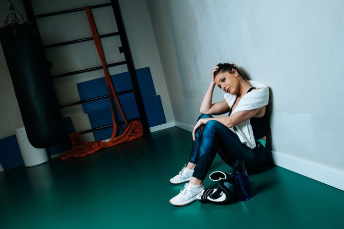 Sportswoman in boxing gloves sitting in gym