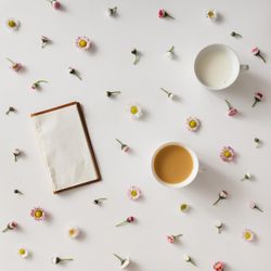 Vintage notebook on light background with colorful flowers and cup of coffee and milk
