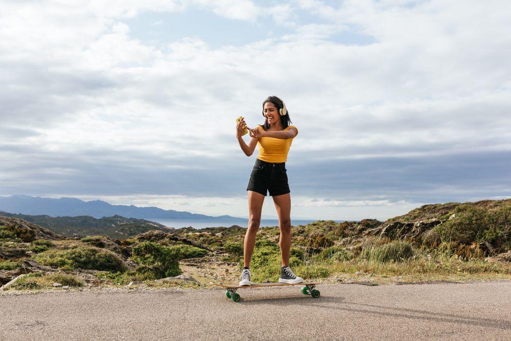 Smiling woman on longboard and taking selfie