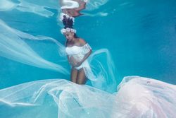Pregnant woman in wreath and dress underwater