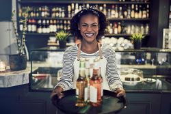Happy woman holding trey of beer and cider in modern bistro
