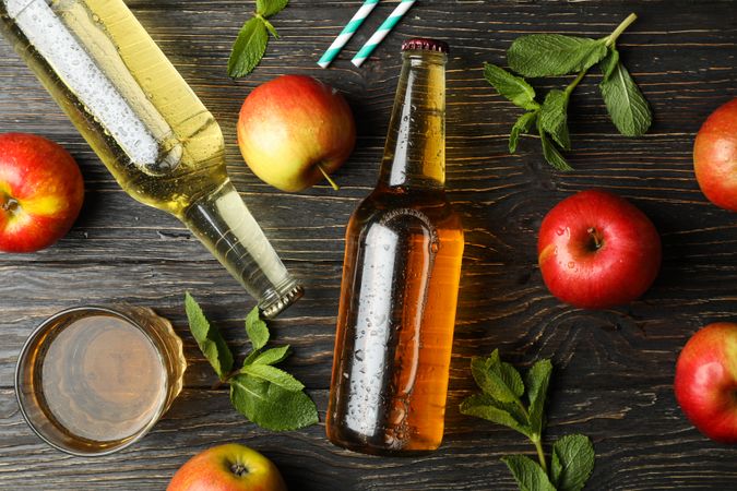 Composition with cider, apples and straws on wooden background