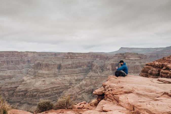 Male relaxing on cliff and admiring picturesque view