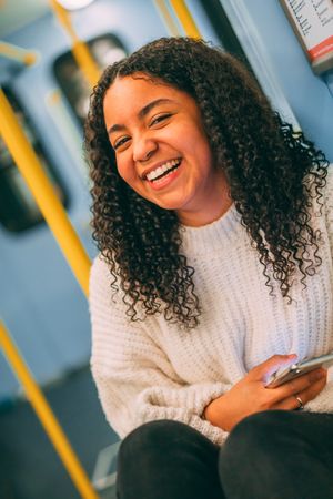 Smiling Black woman using smartphone in transport